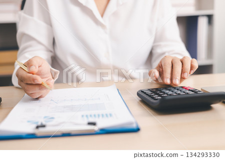 Businessperson using calculator and laptop with financial report on office desk, concept of accounting analysis, budget planning, data management and corporate finance strategy. Businessperson using calculator and laptop with financial report on office desk, concept of accounting analysis, budget planning, data management and corporate finance strategy. 134293330