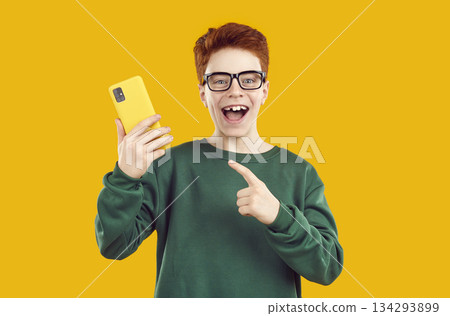 Happy amazed boy pointing his finger at smartphone 134293899