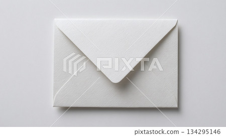 Crisp white envelope lies flat against a light surface, clean lines and shadows create a sense of minimalist elegance, perfect for invitations or business correspondence. 134295146
