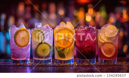 A vibrant array of cocktails with citrus slices and ice, illuminated by colorful lights. A refreshing scene, perfect for celebrations. Each drink offers a unique taste. 134295637