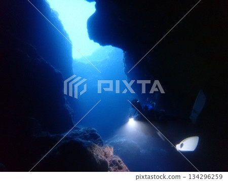 A view of the sea, light and divers from inside an underwater cave 134296259