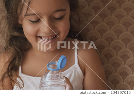 Product innovation: close-up of a girl drinking from a bottle with a modern attached closure Product innovation: close-up of a girl drinking from a bottle with a modern attached closure 134297013