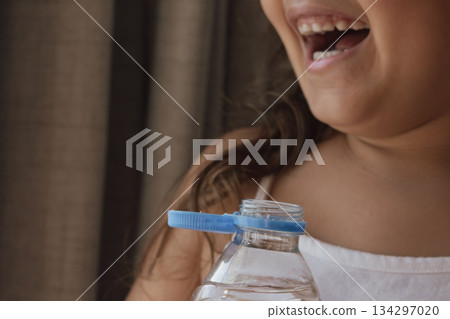 Happy child and water bottle: symbolising health, well-being, and the need for hydration Happy child and water bottle: symbolising health, well-being, and the need for hydration 134297020