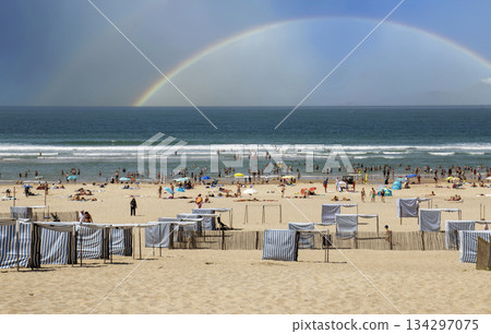 Sunny Beach Scene With Many People and a Rainbow in the Sky Sunny Beach Scene With Many People and a Rainbow in the Sky 134297075