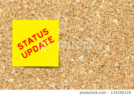 Yellow note paper with word status update on cork board background with copy space 134298120
