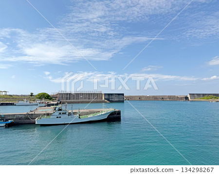Boats docked in a serene harbor with a clear blue sky and calm turquoise waters 134298267