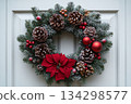 Christmas wreath with red and green leaves and red berries hanging on white door 134298577