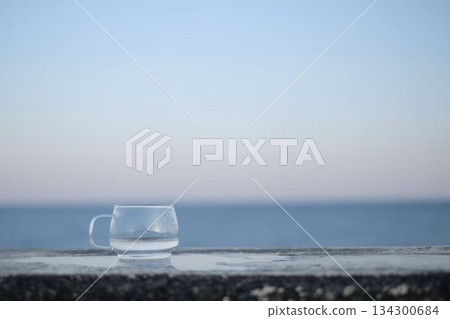 Sunset sea and a clear glass cup Sunset sea and a clear glass cup 134300684