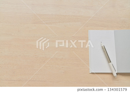 木桌上放著白色記事本和鋼筆。 134301579
