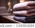 Towels are neatly arranged on a counter in a bathroom. Soft colors reflect the light coming from nearby 134301694