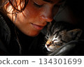 A person smiles while holding a small kitten close. The kitten appears relaxed and content in this moment 134301699