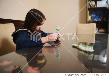 Girl Squeezing Toothpaste Tube At Dining Table With Toothbrush Nearby, Quiet Home Scene Morning Family Girl Squeezing Toothpaste Tube At Dining Table With Toothbrush Nearby, Quiet Home Scene Morning Family 134301713