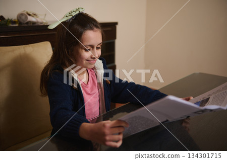 Young Girl Reading A Magazine At Home Table With A Hair Comb 134301715