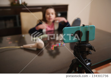 Family Video Setup: Child Talking On Phone While Filming With Tripod At Table 134301736