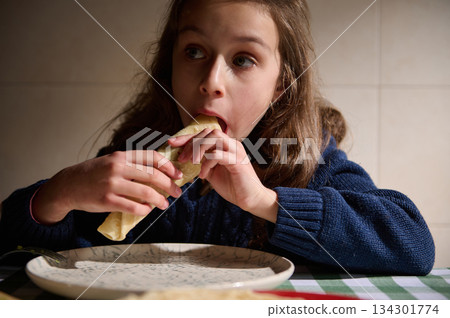 Girl Eating A Wrap At Table In Cozy Kitchen, Casual Indoor Meal Moment Girl Eating A Wrap At Table In Cozy Kitchen, Casual Indoor Meal Moment 134301774