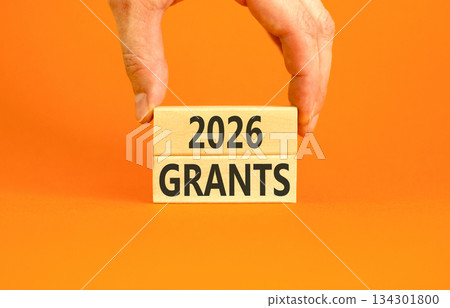 2026 Grants symbol. Concept words 2026 Grants on beautiful wooden blocks. Beautiful orange paper background. Businessman's hand. Business and 2026 grants concept. Copy space. 134301800