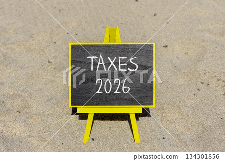 Taxes 2026 new year symbol. Concept words Taxes 2026 on beautiful black blackboard. Beautiful sand beach background. Business and taxes 2026 new year concept. Copy space. Taxes 2026 new year symbol. Concept words Taxes 2026 on beautiful black blackboard. Beautiful sand beach background. Business and taxes 2026 new year concept. Copy space. 134301856