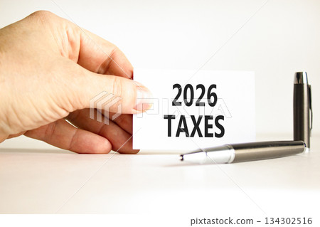 2026 taxes new year symbol. Concept words 2026 taxes on beautiful white card. Beautiful white paper background. Businessman's hand. Business and 2026 taxes new year concept. Copy space. 134302516