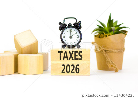 Taxes 2026 new year symbol. Concept words Taxes 2026 on beautiful wooden blocks. Beautiful white paper background. Beautiful black alarm clock. Business and taxes 2026 new year concept. Copy space. 134304223