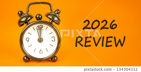 2026 Review symbol. Concept words 2026 Review on beautiful orange paper. Beautiful orange paper background. Beautiful black alarm clock. Business and 2026 review concept. Copy space. 2026 Review symbol. Concept words 2026 Review on beautiful orange paper. Beautiful orange paper background. Beautiful black alarm clock. Business and 2026 review concept. Copy space. 134304312