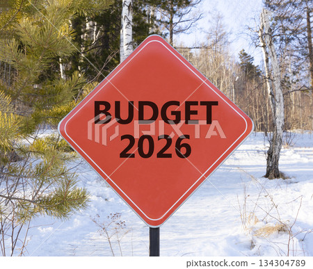 Budget 2026 symbol. Concept words Budget 2026 on beautiful red road sign. Beautiful winter forest background. Business and budget 2026 concept. Copy space. Budget 2026 symbol. Concept words Budget 2026 on beautiful red road sign. Beautiful winter forest background. Business and budget 2026 concept. Copy space. 134304789
