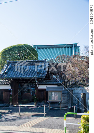 東京王子市，一座綠瓦屋頂的大型寺廟和墓地，在晴朗的藍天下，被冬日的樹木環繞。 134304972