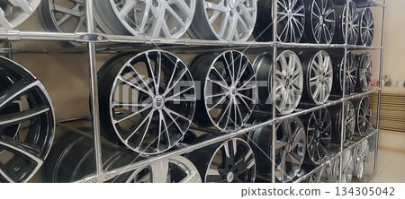 A store display case featuring neatly stacked silver and black alloy wheels on a black and white chrome metal shelf A store display case featuring neatly stacked silver and black alloy wheels on a black and white chrome metal shelf 134305042