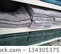 On store shelves, customers can find neatly arranged multicolored cotton towels in various sizes. The towels are stacked neatly for easy viewing and selection. 134305375