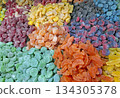 Brightly colored candied marmalade sweets fill the table at a market, attracting attention with their various shapes and sizes. The sweets create a visual treat of sugar and flavor. 134305378
