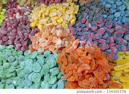 Brightly colored candied marmalade sweets fill the table at a market, attracting attention with their various shapes and sizes. The sweets create a visual treat of sugar and flavor. Brightly colored candied marmalade sweets fill the table at a market, attracting attention with their various shapes and sizes. The sweets create a visual treat of sugar and flavor. 134305378