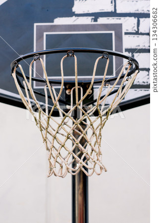 Detailed closeup of an aged basketball hoop with worn net and graphic backboard, capturing an authentic outdoor sports atmosphere. Detailed closeup of an aged basketball hoop with worn net and graphic backboard, capturing an authentic outdoor sports atmosphere. 134306682