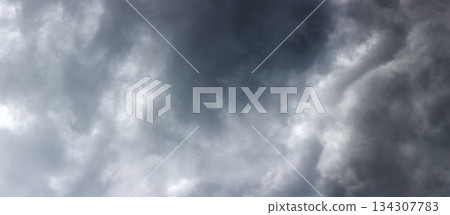 Ominous storm clouds looming in the daytime sky Ominous storm clouds looming in the daytime sky 134307783