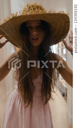 A Young Woman Wearing a Straw Hat Alongside a Lovely Pink Dress Enjoying the Outdoors 134308192