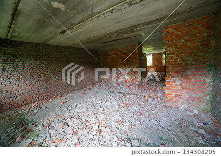 Desolate interior of abandoned building with brick walls and rubble 134308205