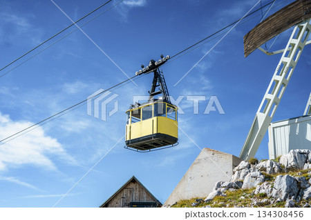 Cable car in Dachstein against the sky. Yellow suspended gondola on a cable car in the Austrian Alps Cable car in Dachstein against the sky. Yellow suspended gondola on a cable car in the Austrian Alps 134308456