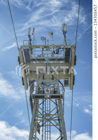 Cable car tower with satellite dishes on top of a mountain against a blue sky on a sunny day in the Austrian Alps 134308457
