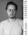 Black and white portrait of young man wearing glasses indoors 134308578