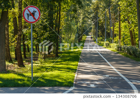 No Dogs Allowed Sign on Paved Path in Peaceful Park No Dogs Allowed Sign on Paved Path in Peaceful Park 134308706