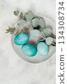Easter colored eggs, in turquoise tones, on a gray plate, with a branch of eucalyptus, Easter card, top view, no people 134308734