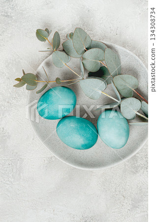 Easter colored eggs, in turquoise tones, on a gray plate, with a branch of eucalyptus, Easter card, top view, no people Easter colored eggs, in turquoise tones, on a gray plate, with a branch of eucalyptus, Easter card, top view, no people 134308734