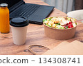 work at home on a laptop, there is food on the table, salad, coffee and juice, delivery, there are no people, 134308741