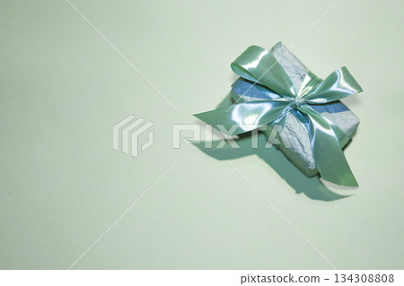 Mint color gift box wrapped with satin ribbon on a minimal festive background Mint color gift box wrapped with satin ribbon on a minimal festive background 134308808