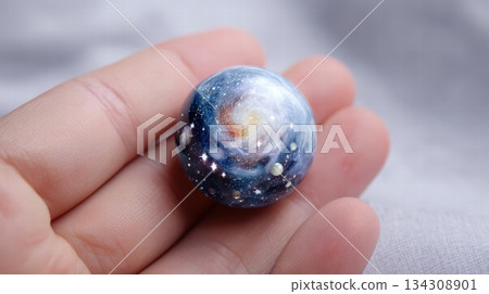 Cosmic Galaxy Marble Held Between Fingers, A Small Sphere Of Space, Stars, And Wonder 134308901