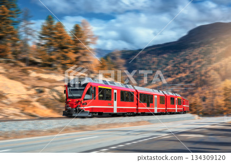 Red modern passenger train is moving on railway in swiss alps Red modern passenger train is moving on railway in swiss alps 134309120