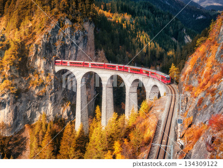 Aerial view of modern red train on Landwasser viaduct in autumn 134309122