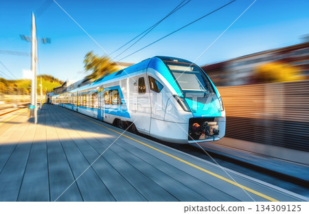 High-speed blue passenger train moving at railway station 134309125