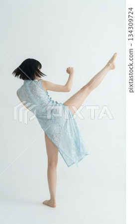 一位身著中國傳統服飾的功夫女從背後高高踢腿 134309724