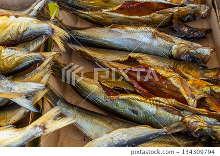 Golden brown smoked fish stacked indoors at market stall 134309794