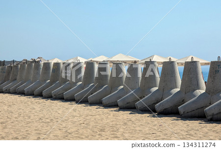 a row of reinforced concrete tetrapod blocks on a sandy beach by the sea a row of reinforced concrete tetrapod blocks on a sandy beach by the sea 134311274