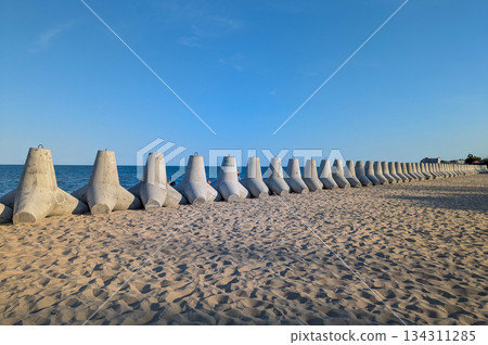A long row of tetrapods stretches along the coastline. 134311285